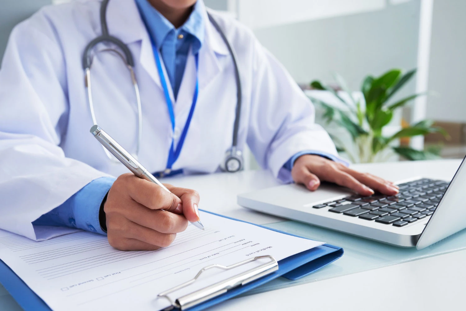 hands-unrecognizable-female-doctor-writing-form-typing-laptop-keyboard-opt